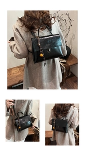Details eines schwarzen Lederrucksacks mit goldener Schnalle und Glockenanhänger im Alltag