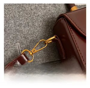 Close-up of premium gold hardware and leather stitching on dark brown shoulder bag