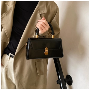 Detail of glossy black patent leather bag featuring elegant gold vintage metal lock and hardware