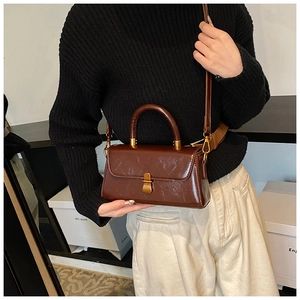 Detail of vintage dark brown leather handbag with bronze twist lock on a white background