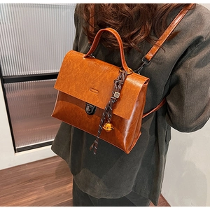 Detail eines braunen Vintage Lederrucksacks mit Metallschloss und Kordelanhänger
