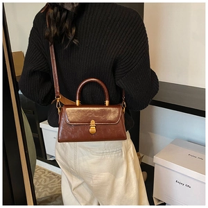 Detail of vintage brown leather handbag with gold metal clasp and adjustable strap