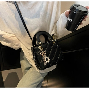 Détail du sac matelassé noir avec clous étoiles dorés et breloque perle et nœud