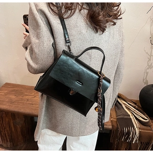 Polierte schwarze Lederhandtasche mit dekorativem Seidenschal an einem Model im Blazer