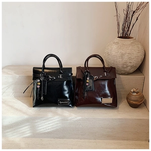 Gros plan de sacs à dos en cuir verni brillant noir et bordeaux avec boucles métalliques