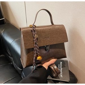Détails d'un sac à main rétro en cuir marron foncé avec pompon et clochette dorée