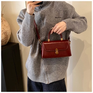 Detail of vintage burgundy shoulder bag with glossy leather texture and gold hardware