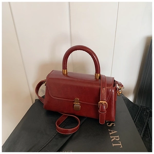 Detail of dark red vintage square bag with polished synthetic leather and bronze clasp