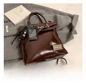 Vue détaillée d'un sac à dos en cuir verni marron foncé brillant avec plaque logo