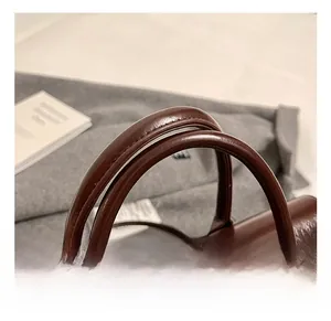 Détail rapproché des poignées cylindriques douces sur un sac à dos en cuir marron foncé