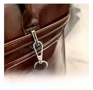 Gros plan du fermoir mousqueton argenté et de la sangle en cuir sur le sac à dos brun
