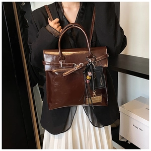 Detail of vintage dark brown faux leather backpack with belt buckle and tassel charm