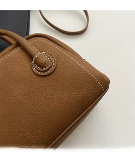 Close-up of brown leather bag with lychee texture and white stitching details