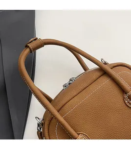 Detail of brown shell bag showing white contrast stitching and premium pebbled leather