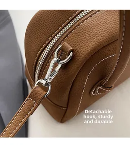 Close-up of brown lychee leather bag with silver metal hooks and contrast stitching