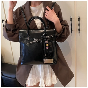 Detail of vintage black oil-wax leather backpack with metal buckle and charms on a model