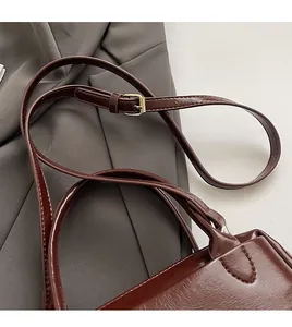 Détail de la bandoulière réglable avec boucle dorée sur un sac à main en cuir marron