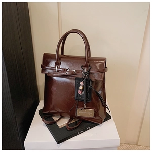 Macro detail of glossy brown vintage faux leather texture and reinforced handbag handle