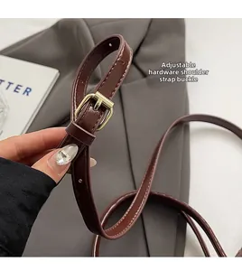Détail de la bandoulière réglable en cuir marron foncé avec boucle dorée polie