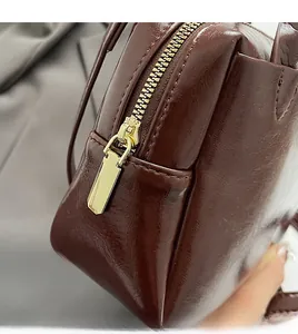Détail d'un sac à main en cuir marron foncé avec fermeture éclair dorée fluide