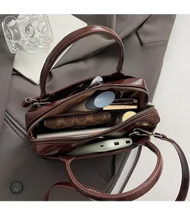 Vue de dessus du sac à main en cuir verni marron foncé montrant les compartiments intérieurs