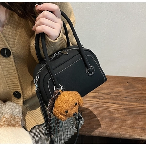 Détail du mini sac bowling noir avec surpiqûres blanches et charme d'ours en peluche
