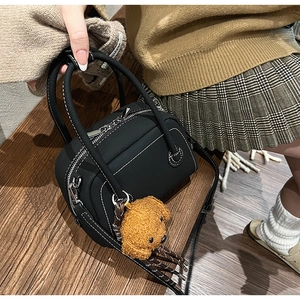 Détail du sac bowling noir avec surpiqûres blanches et breloque chien en peluche