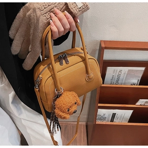 Détail d'un sac bowling en cuir jaune gingembre avec pendentif ours en peluche marron