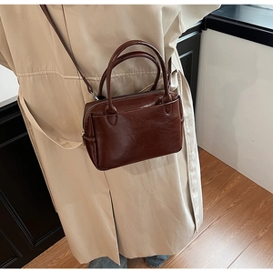 Detailansicht einer dunkelbraunen Handtasche aus Ölwachsleder zum Khaki-Mantel