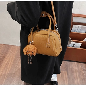 Détail d'un sac bowling en cuir caramel avec un charmant porte-clés caniche en peluche