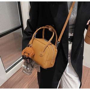 Detail of yellow pebbled leather shell bag with a cute brown poodle plush charm