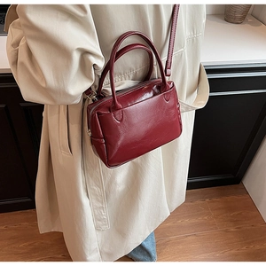 Seitenansicht einer Frau mit weinroter Lederhandtasche und beigem Trenchcoat im Freien