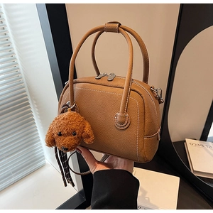 Close-up of brown lychee leather bowling bag with cute teddy bear plush charm