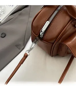 Detail of high-gloss silver zipper and metal hook on a vintage brown leather handbag