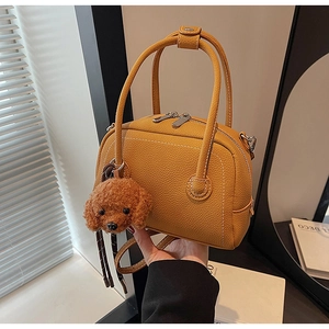 Close-up of yellow bowling bag with lychee texture and cute teddy dog plush charm
