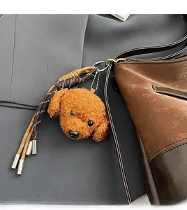 Charmant pendentif chiot en peluche caramel avec pompons sur un sac à main en cuir