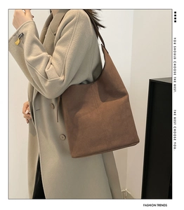 Detail of a brown large capacity tote bag with adjustable strap worn on the shoulder