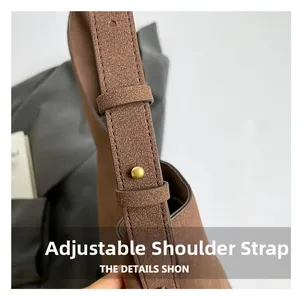 Detailed macro view of the brown suede bag featuring an adjustable shoulder strap with gold studs