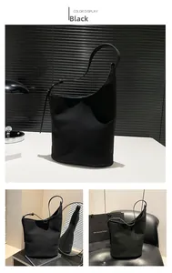 Detail view of the black bucket bag showing asymmetric cut and adjustable strap