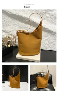 Detail view of brown suede bucket bag with adjustable strap and vertical stitching accents