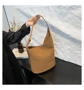 Detailed view of the camel suede bucket bag showing soft texture and adjustable shoulder strap
