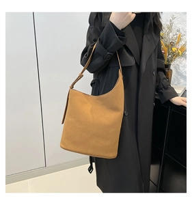 Close-up of caramel shoulder tote bag with vertical stitching and adjustable strap on model