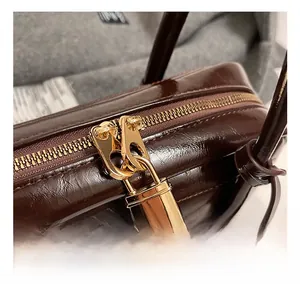 Detail of premium oil-wax leather texture and golden padlock zipper on the tote bag