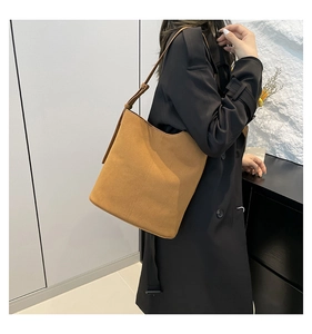 Detail view of adjustable strap and white stitching on brown suede bucket bag
