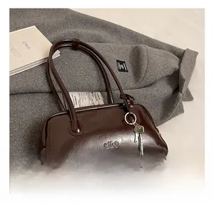 Detail view of deep brown oil wax leather handbag with embossed logo and metal key charm