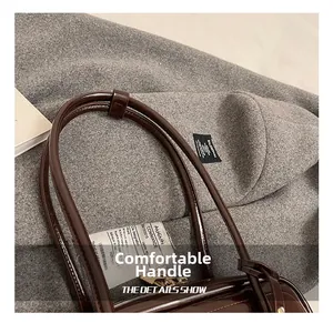 Detail showing high-gloss dark brown leather bag with thick rounded comfortable handles