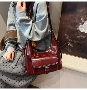 Détail du cabas en cuir PU bordeaux avec coutures blanches et breloque en ours
