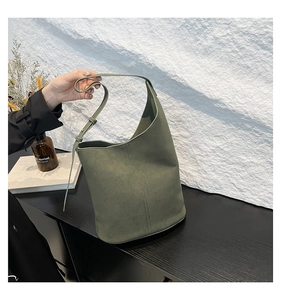Detailed view of an olive green suede bucket bag with adjustable shoulder straps