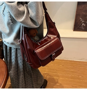 Détail du sac hobo bordeaux en similicuir avec coutures contrastées et poche à boucle avant