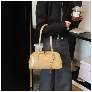Close-up of beige glossy leather Boston bag with gold zipper and embossed logo details